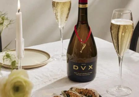 A bottle and two glasses of Mumm DVX Rosé with a plate of Grilled Peach And Prosciutto Salad