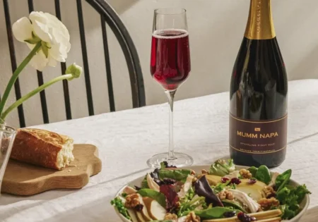 A bottle and glass of Mumm Sparkling Pinot Noir alongside a wide bowl of Turkey Salad With Cherry Vinaigrette